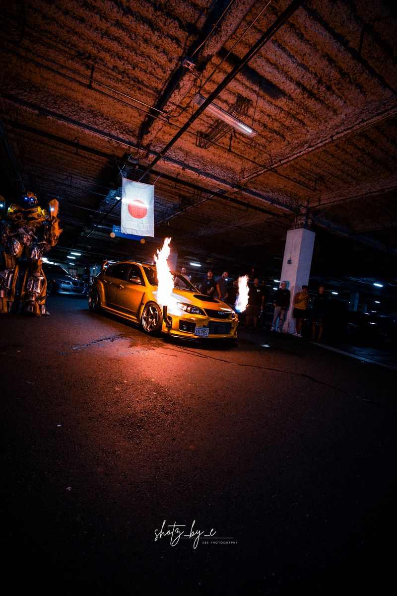 Orange car spitting exhaust flames in a garage